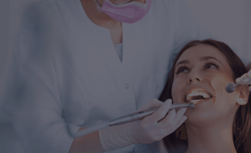 Dentist treating a smiling female patient.