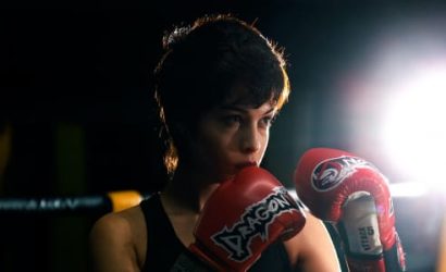 Boxer wearing red gloves in dim light.