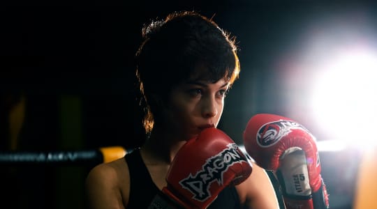 Boxer wearing red gloves in dim light.