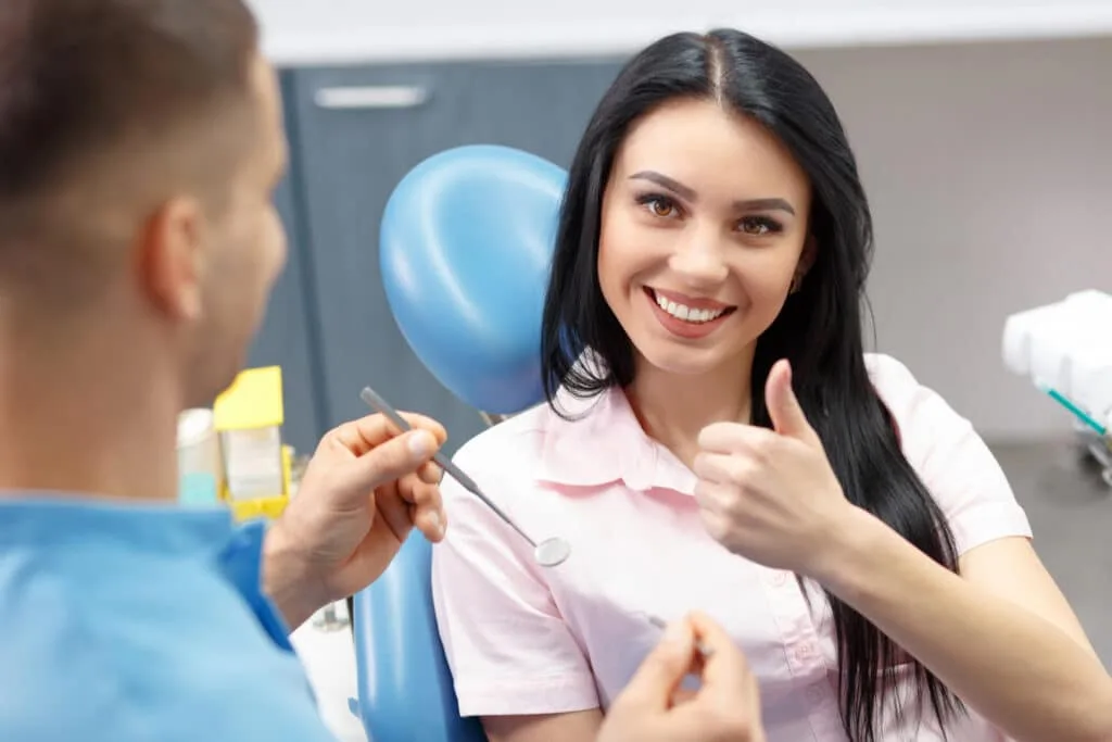 Woman giving thumbs up at the dentist's office.