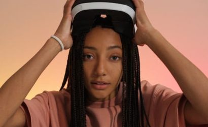 Young woman adjusting a VR headset with a neutral expression.