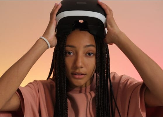Young woman adjusting a VR headset with a neutral expression.