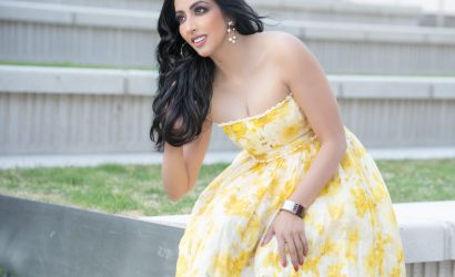 A woman in a yellow floral dress sitting on outdoor steps.