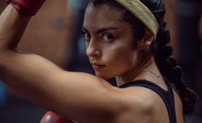 Focused female boxer in training with gloves and headband.