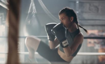 A woman intensely boxing in a gym setting.