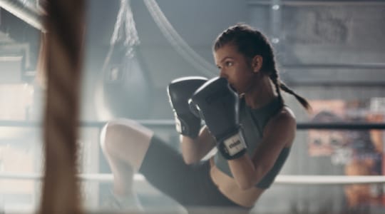 A woman intensely boxing in a gym setting.